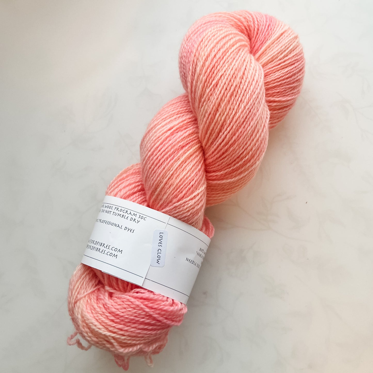 Peach-colored yarn skein on a white surface